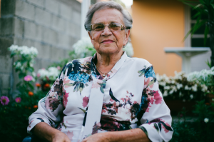 Senior woman in wheelchair smiles outside of home