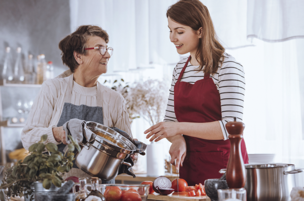 female support worker and older woman cooking in kitchen at home