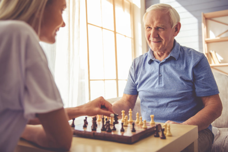 Older person playing chess with a Support Worker