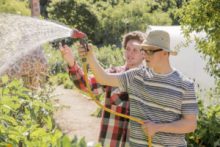Two men help out at the farm by doing some gardening.