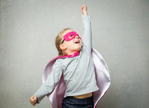 Little girl pretending that she is flying wearing a cloak and mask