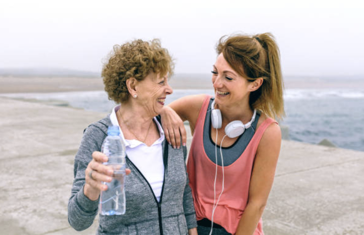 Senior woman smiling with daughter in outdoor setting after engaging in physical activity