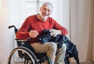 Older person in a wheelchair petting his dog