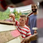 A child helps paint the hen hut at the farm.
