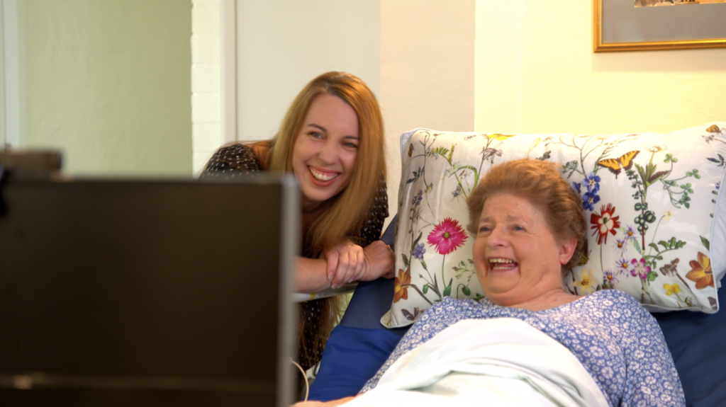Mable client Trish and her support worker Julia watch TV together.