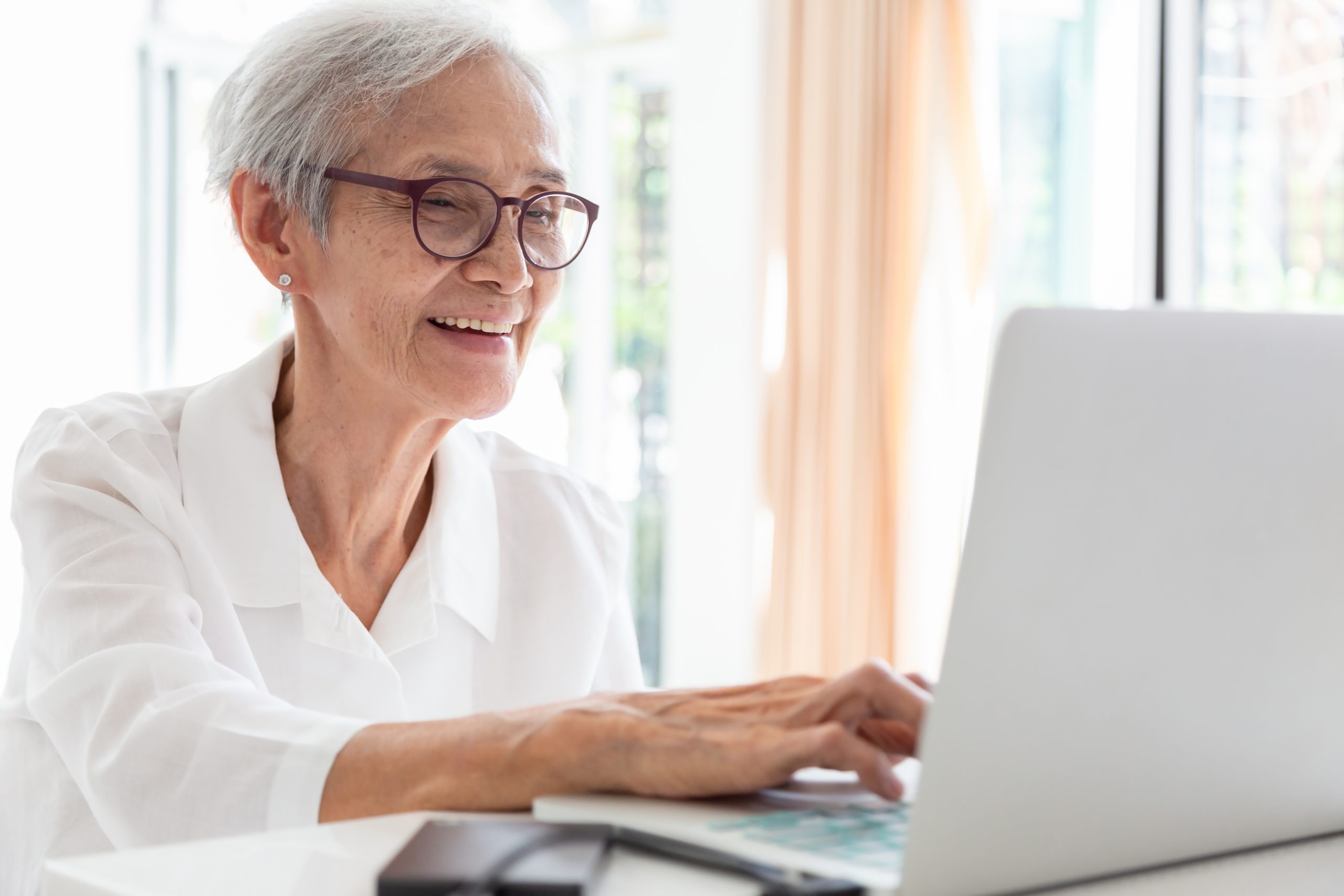 Older woman working with laptop at table in home
