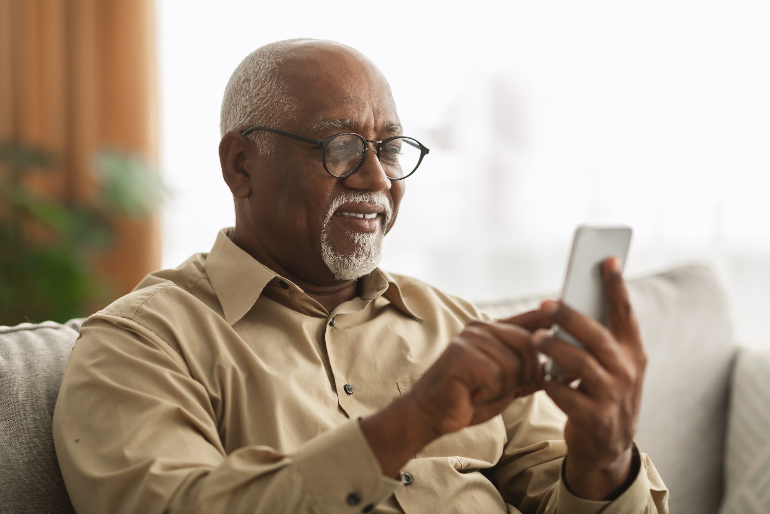 Senior Man Texting On Smartphone Using Application At Home