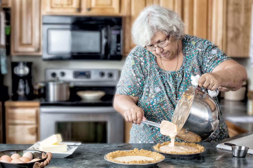 An older woman baking at home in the kitchen.