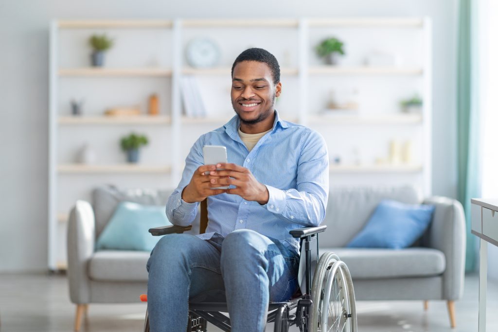 Man using a wheelchair smiling at his smartphone.