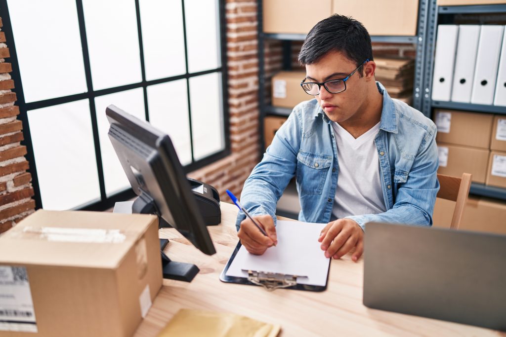 Man living with down syndrome writing on document reviews his NDIS plan