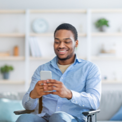 Man in wheelchair smiling while using smartphone device