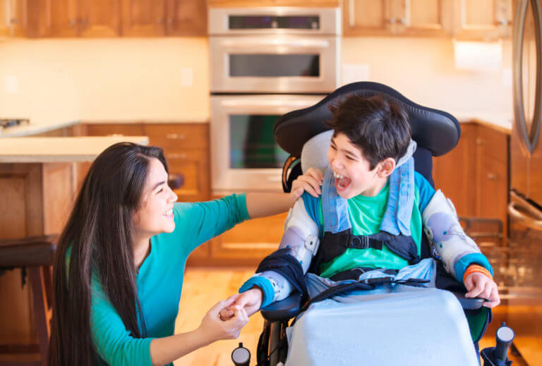 A child using a wheelchair laughing with his support worker.