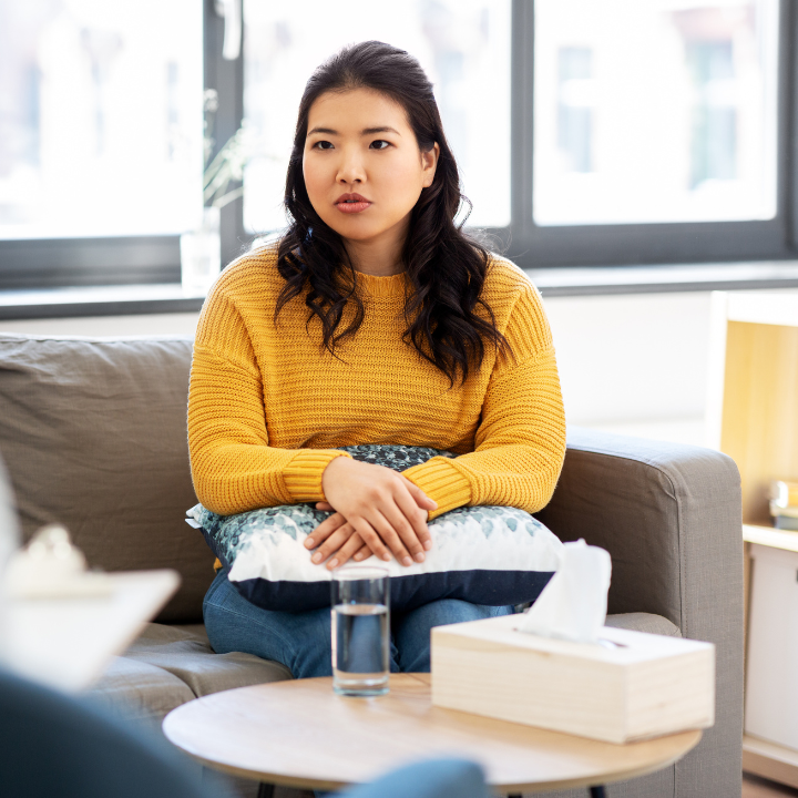 young woman having conversation with therapist on couch