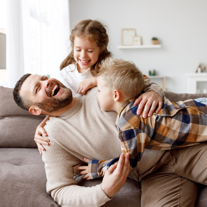 father with children playing at home living room