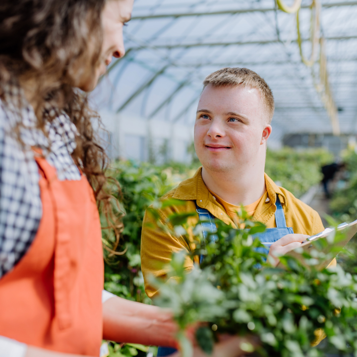 A young man with Down syndrome gardening with his support worker.