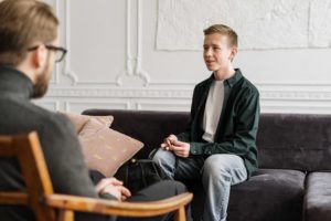 man speaking to allied health worker while sitting on couch
