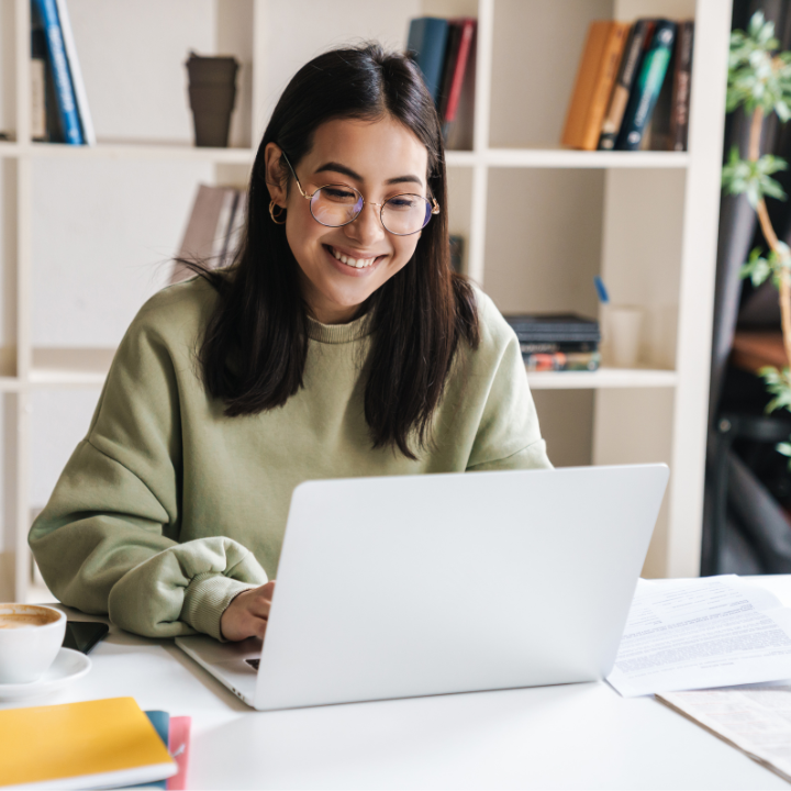 Cheerful woman in green sweater works on laptop in bright home office