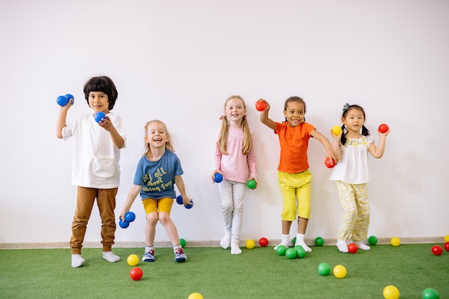 group of children holding and throwing colourful balls at the camera