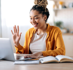 smiling woman in casual clothes uses laptop for online video conference with colleagues or friends