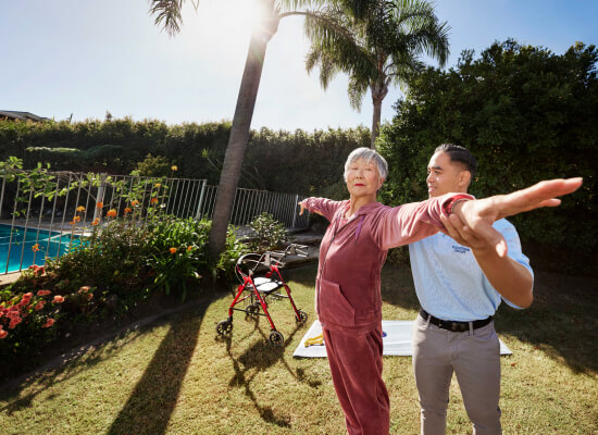 Person exercises outdoors, aided by caregiver
