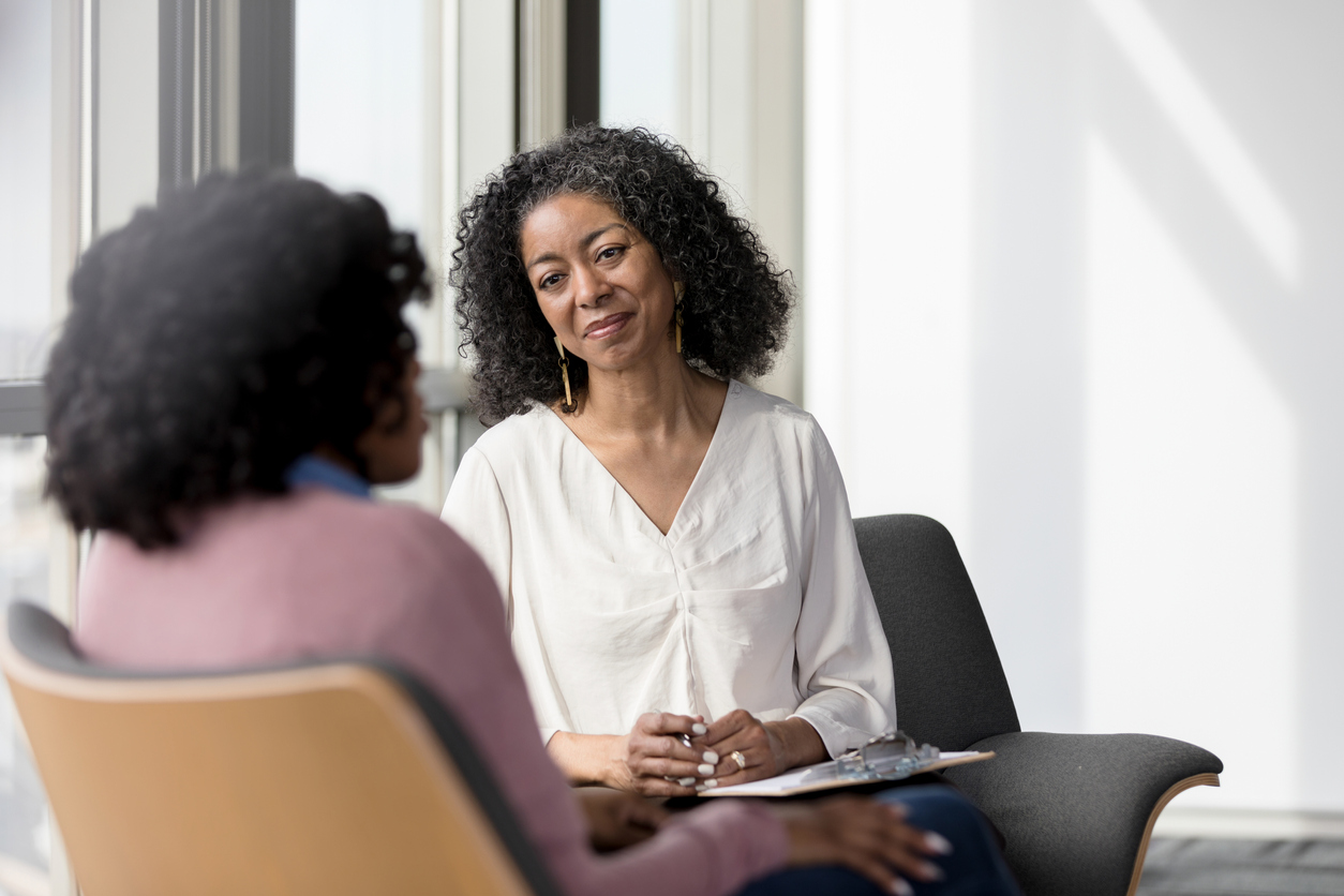 Mature female counselor listens compassionately to female client