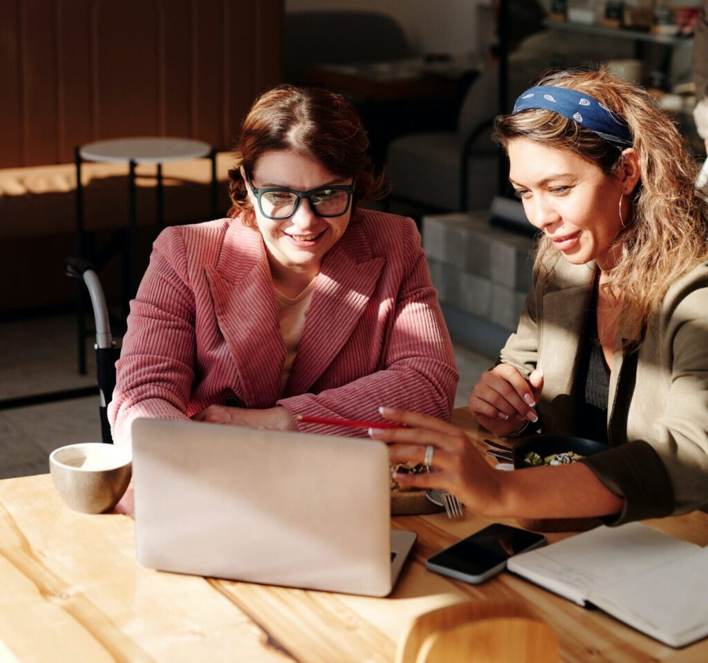 Two women work at a laptop together.