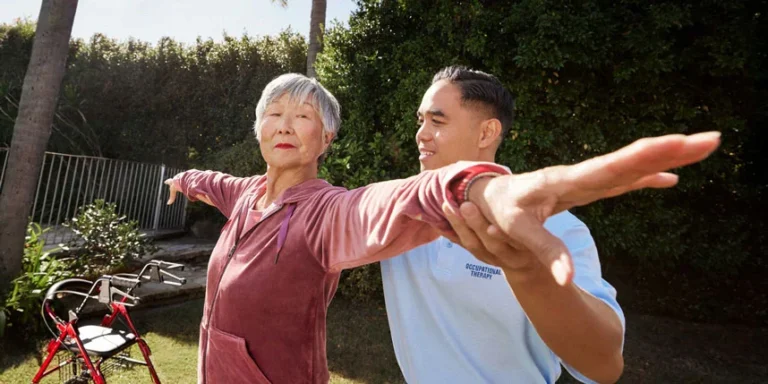 Exercising person helped by caregiver outdoors.