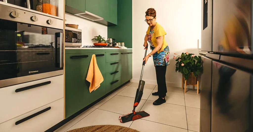 Support worker mops the kitchen floor in their client’s home.