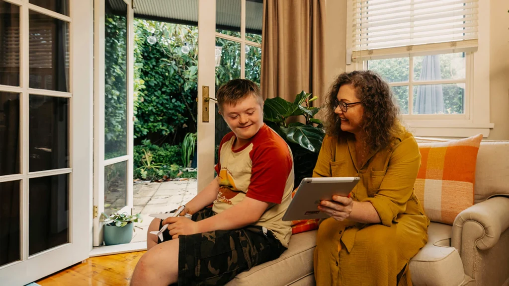 Mum shows son with disability Mable support workers on her tablet.