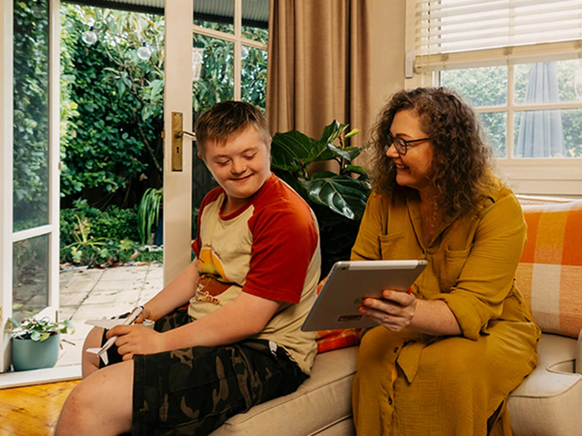 Mum shows son with disability Mable support workers on her tablet.