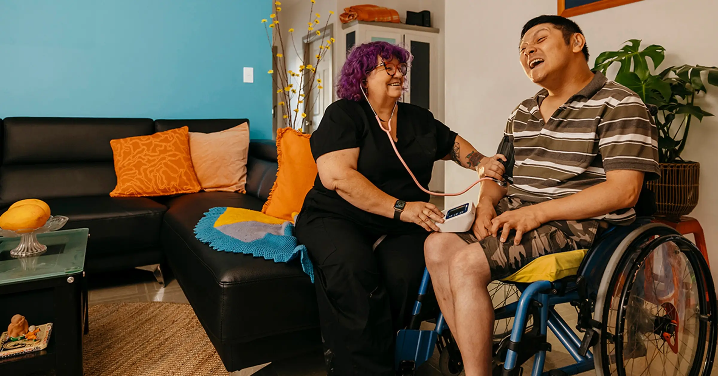 Registered Nurse takes blood pressure reading of client with cerebral palsy in wheelchair.