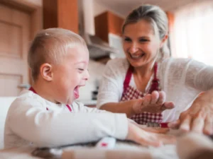 A young boy with Down syndrome in the kitchen with his support worker.
