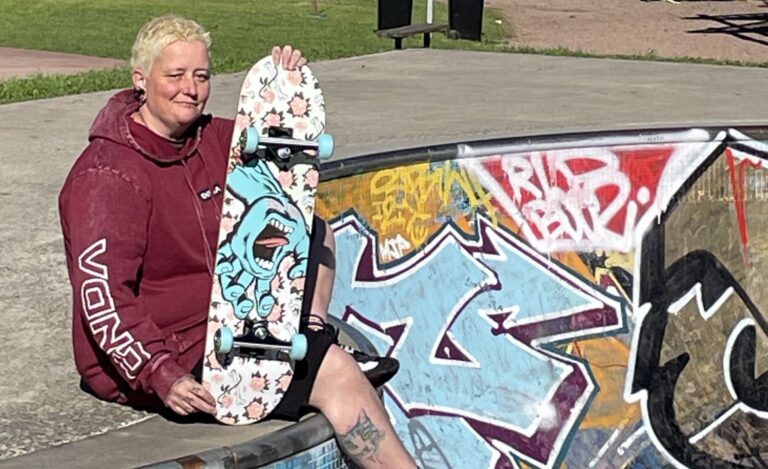 Charlie sits with their skateboard