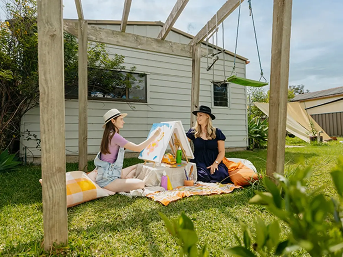 Occupational Therapist and teenager with autism paint outdoors for art therapy support session.