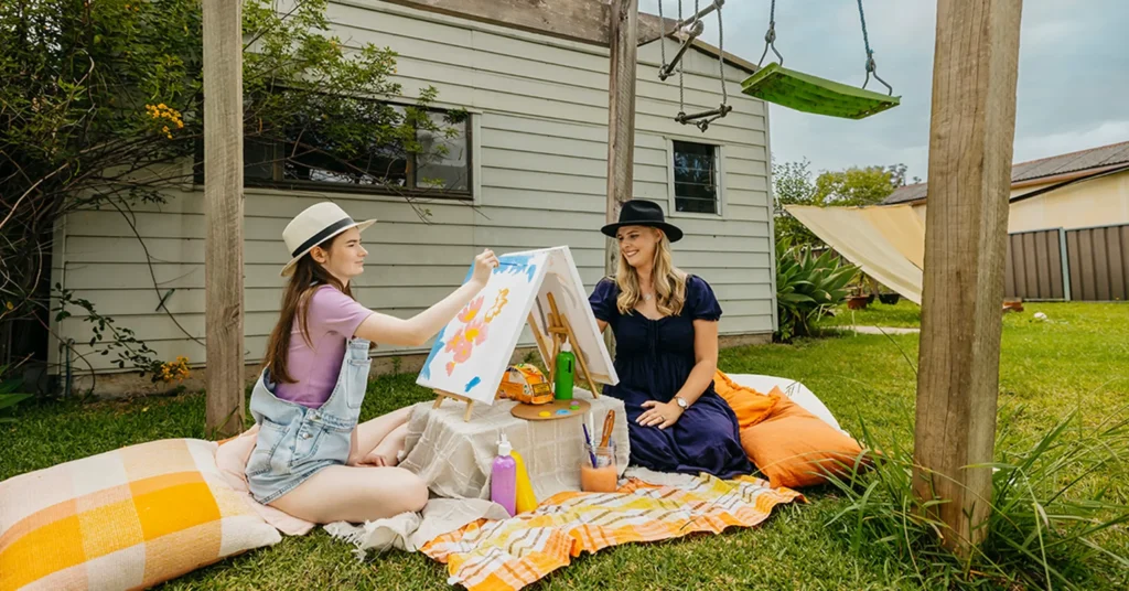 Occupational Therapist and teenager with autism paint outdoors for art therapy support session.