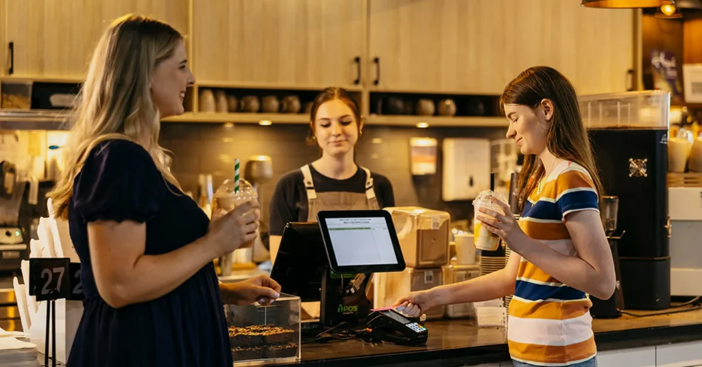 Occupational Therapist watches as teenager with autism pays for milkshakes during support session.