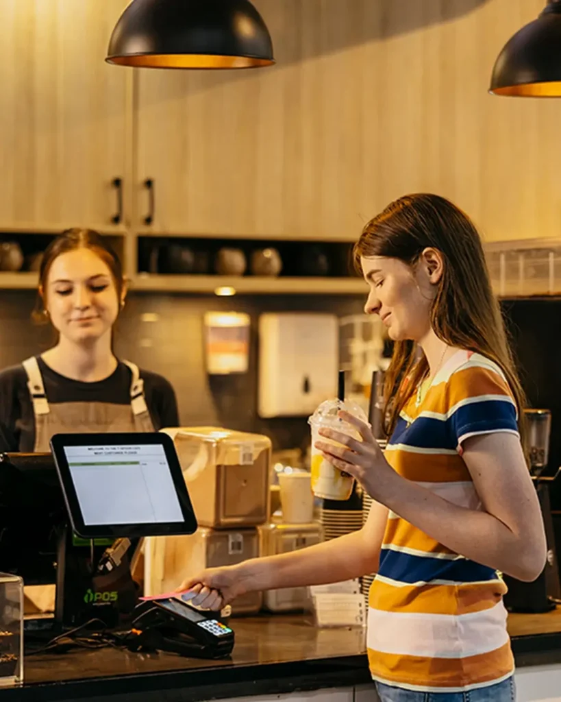 Occupational Therapist watches as teenager with autism pays for milkshakes during support session.