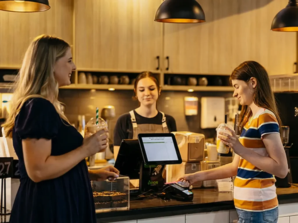 Occupational Therapist watches as teenager with autism pays for milkshakes during support session.