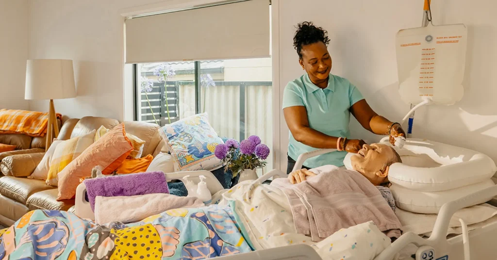 Support worker washes the hair of an older person living with dementia as they lay in bed at home.