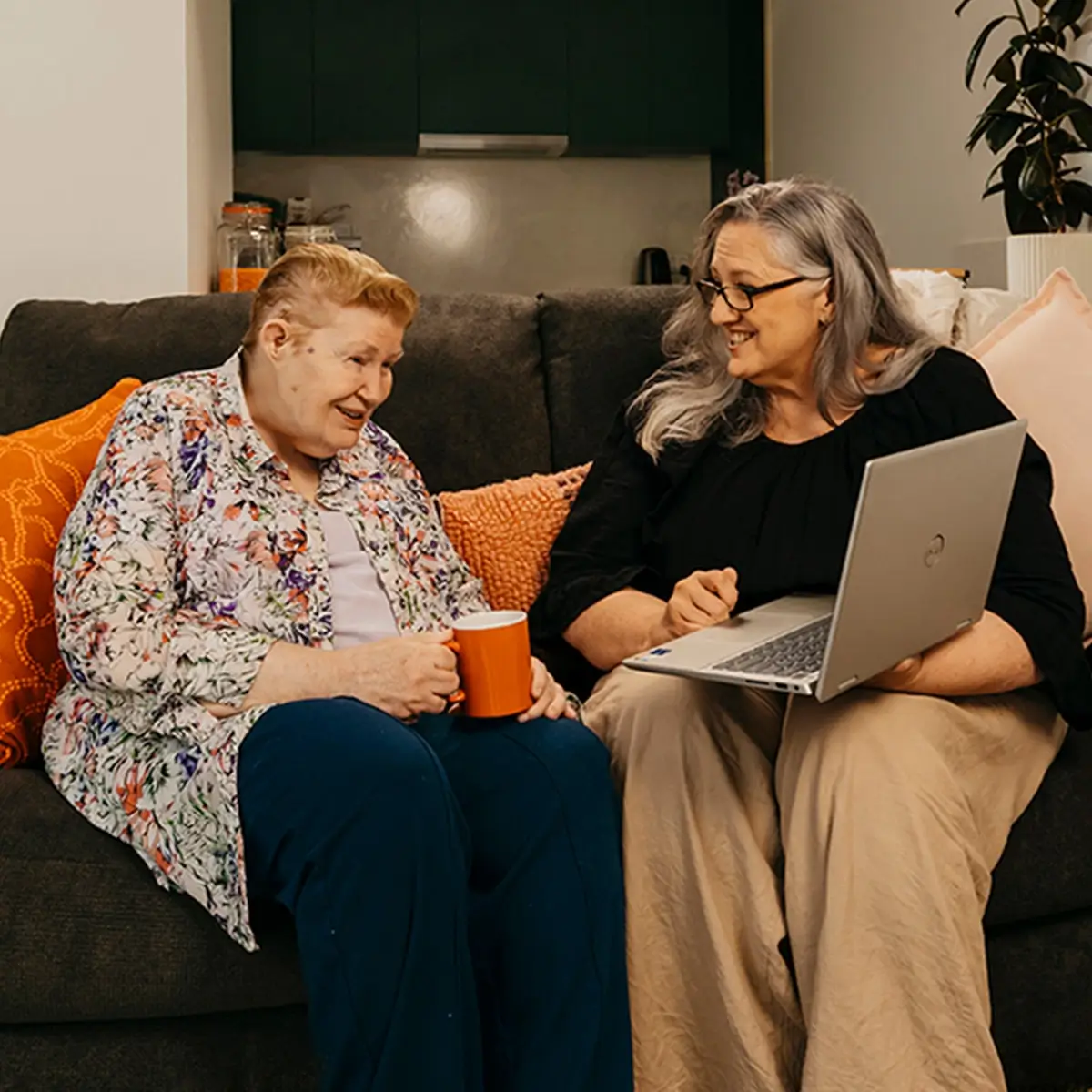 Support coordinator sits with an older client and their laptop to search support workers on Mable.