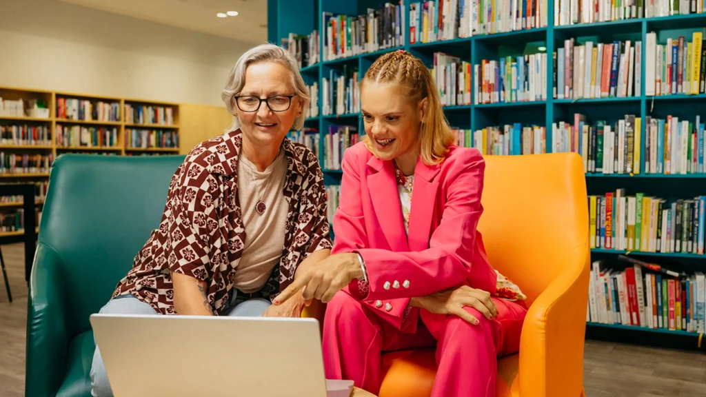 Support coordinator and their client with disability sit at a laptop to search for support workers.