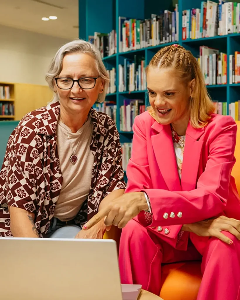 Support coordinator and their client with disability sit at a laptop to search for support workers.