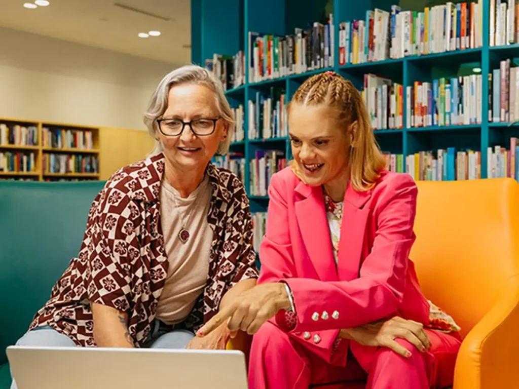 Support coordinator and their client with disability sit at a laptop to search for support workers.