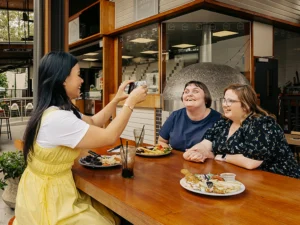 Mable clients Abby and Shannan eat lunch at a restaurant with their support worker Rossiana.