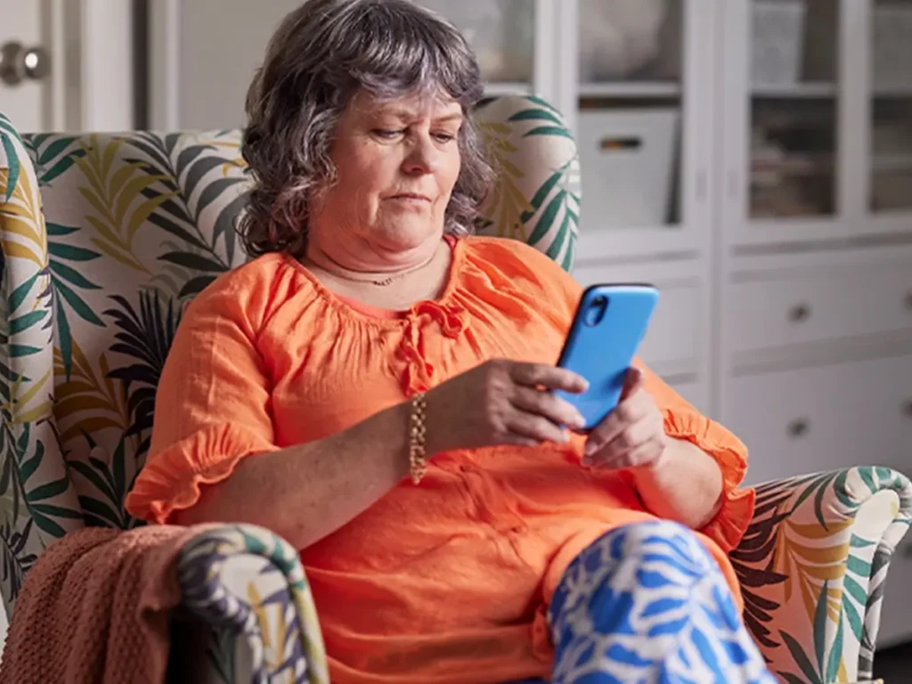 Support worker sitting in armchair while looking at their phone.