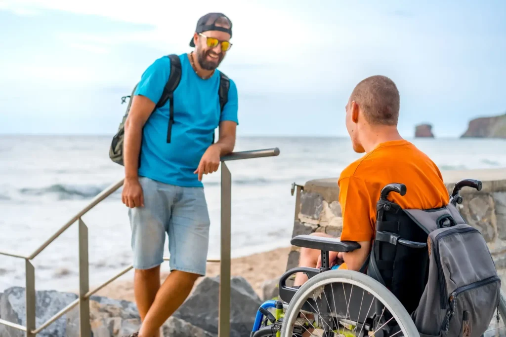 A wheelchair user and their support worker at the beach