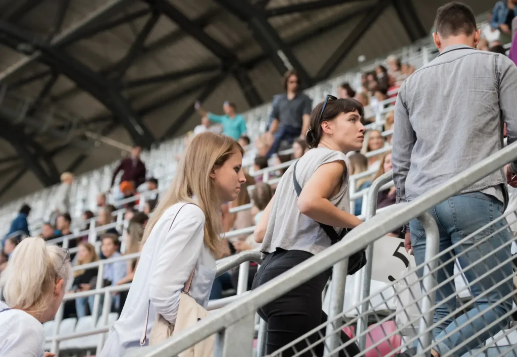 Two women and a man find thier seats in a stadium