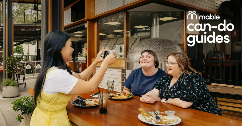 Mable clients Abby and Shannan eat lunch at a restaurant with their support worker Rossiana.