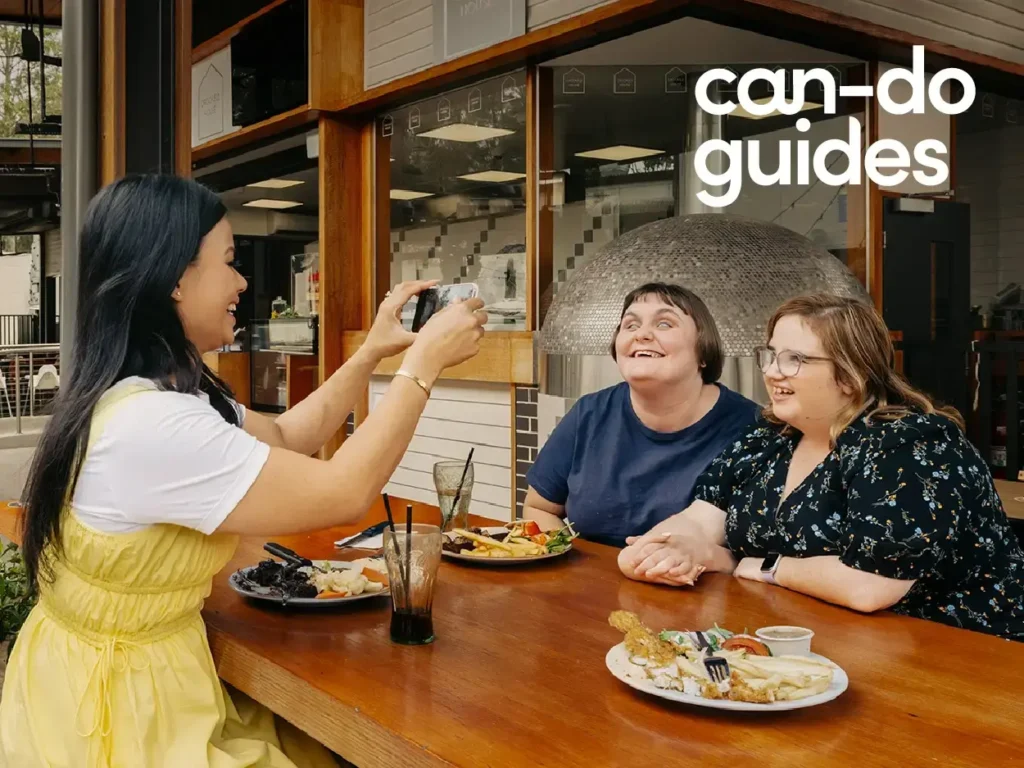 Mable clients Abby and Shannan eat lunch at a restaurant with their support worker Rossiana.