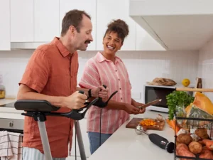 Support worker dicing pumpkin at the kitchen bench while talking to client with multiple sclerosis using a standing aid.